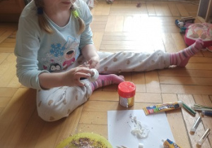 Dziewczynka siedzi i ozdabia pisanki ze styropianu