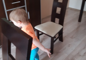 chłopiec idzie slalomem między krzesłami w domu