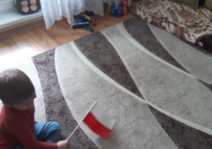 chłopiec siedzi na dywanie z flagą Polski