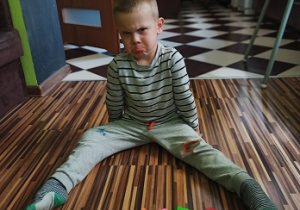 chłopiec siedzi na dywanie przed papierowymi motylkami