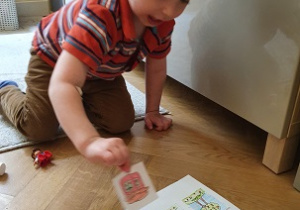 chłopiec przykleja obrazki na kartkę