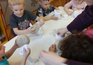 Dzieci wykonują bałwanki z białej skarpetki i sizalu