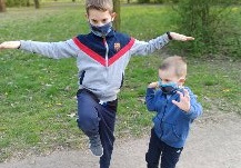 chłopcy w parku udają bociany stojące na jednej nodze