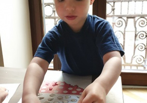 chłopiec siedzi przy stoliku i wykonuje pracę