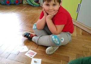chłopiec siedzi przy kolorowych obrazkach