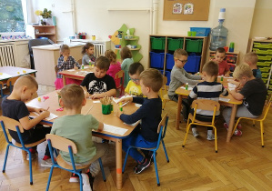 dzieci przyklejają na kartkę wycięte koła