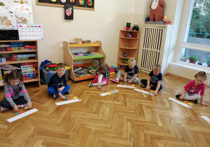 widok z przodu na dzieci siedzące na podłodze które układają koła według polecenia