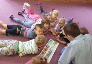Dzieci słuchają bajki i oglądają obrazki w książce