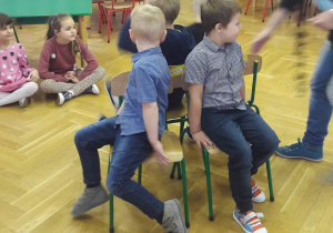 Dzieci bawią się w krzesełka. Chłopcy siedzą na swoich krzesłach i czekają na muzykę by tańczyć.