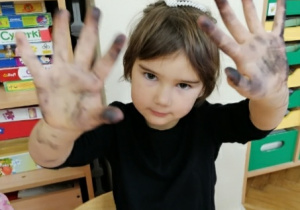 Dziewczynka pokazuje brudne ręce po węglu