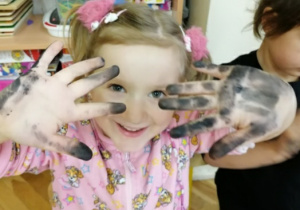 Dziewczynka pokazuje brudne ręce od węgla