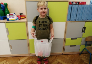 chłopiec pozuje do zdjęcia trzymając torbę z nagrodami