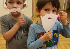 chłopcy pozują do zdjęcia ze sztucznymi wąsami oraz brodą i czapką św. Mikołaja