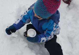 Dziewczynka naklada śnieg do miseczki