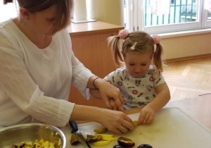 Pani pomaga dziewczynce kroić śliwkę