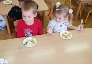 Dzieci jedzą przy stole swoją sałatkę
