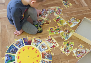 Chłopiec uklada puzzle na podłodze