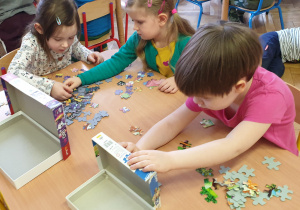 Dziewczynki przy stole układają puzzle