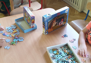 Chlopcy siedzą przy stole i układają puzzle