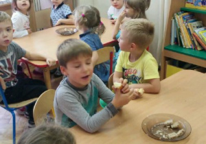 Dzieci przy stoliku próbują kawałka chleba żytniego i razowego