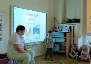 Chłopiec stoi przy tablicy interaktywnej