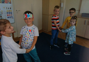 Dzieci tańczą w parach i małych kołach przy muzyce.