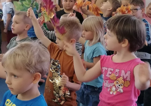 Dzieci tańczą i machają liśćmi do muzyki