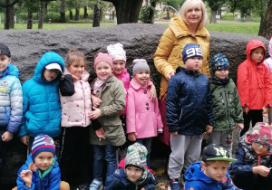 Dzieci stoją z panią w parku
