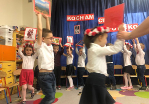 Dzieci trzymają obrazki z elementami charakterystycznymi dla Polski