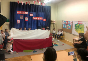 Dzieci tworzą flagę Polski z materiału 