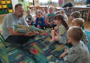 Pan pokazuje dzieciom obrazki w książce