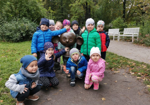Zdjęcie grupowe dzieci stoją przy pomniku Plastisia