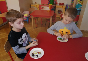 Chłopcy siedzą przy stoliku i lepią z plasteliny
