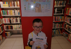 Chłopiec stoi z dyplomem przy pracy