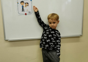 Chłopiec stoi przy tablicy i pokazuje prawo dziecka